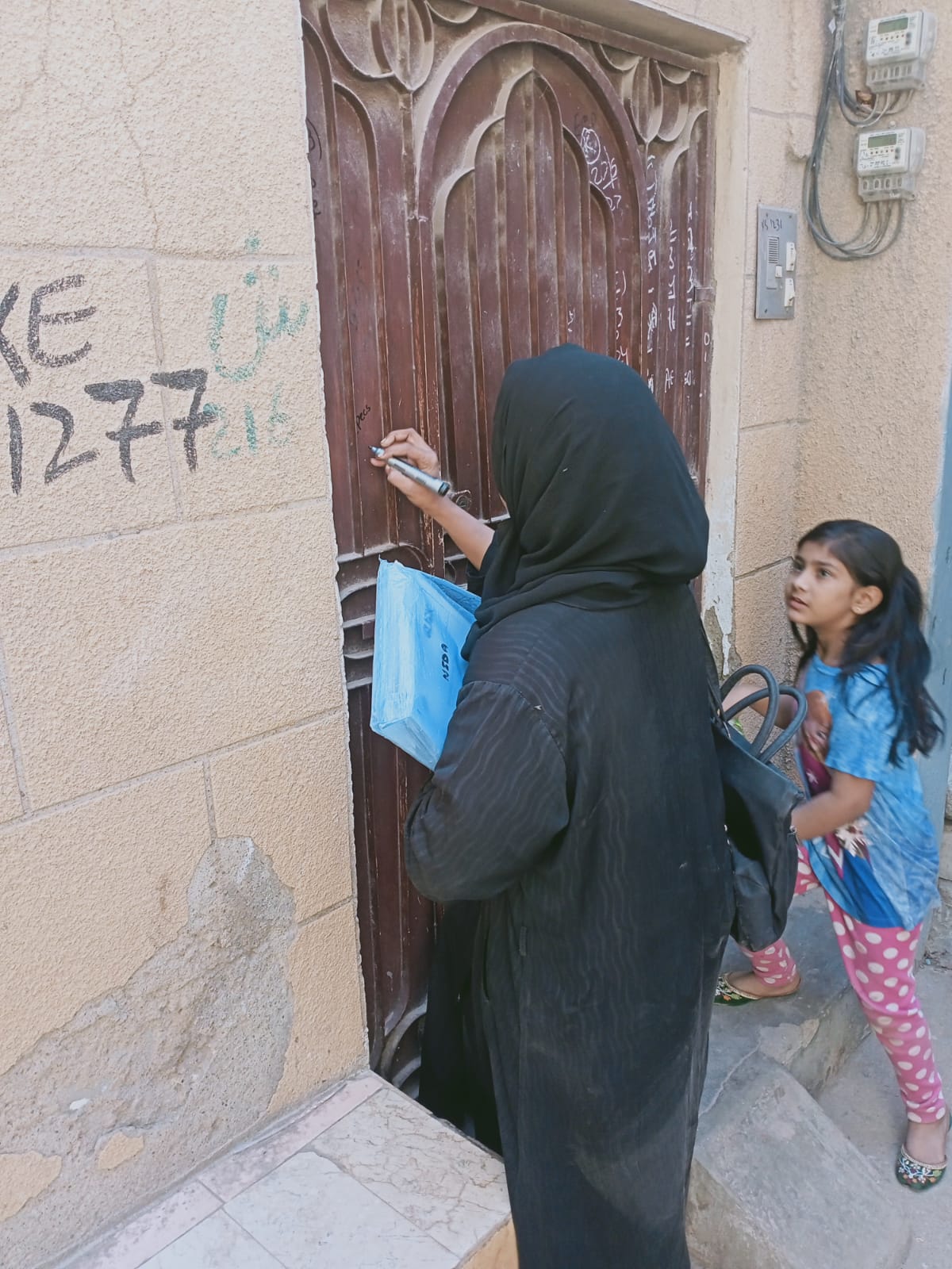Field surveyor marking house numbers - Click Karachi survey enumeration